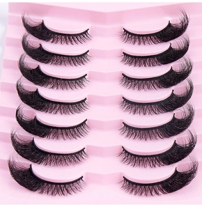 Macro detail of 7 pairs of thick fox-eye false eyelashes arranged on a pink tray