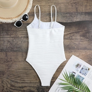 Flat lay of white one-piece swimsuit with wavy ribbed texture and metal strap buckles