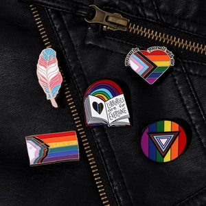 Nahaufnahme von Regenbogen-Emaille-Pins an einem Revers aus schwarzem Strukturleder
