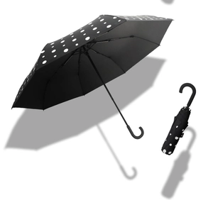 Detail of opened and folded black umbrella with white polka dots and hook handle