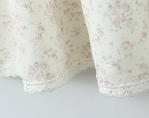 Détail de l'imprimé floral avec dentelle blanche délicate sur l'ourlet de la robe