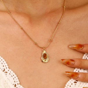 Close-up of a gold tiger eye pendant necklace on a model with white lace clothing