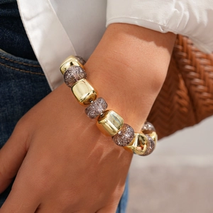 Detail of chunky retro bracelet with gold beads and purple resin worn on wrist