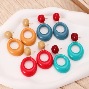 Flat lay of colorful geometric resin earrings in vibrant orange, blue, and red on white tray