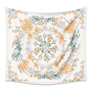 Detail of square tapestry with orange and green floral mandala pattern on white fabric