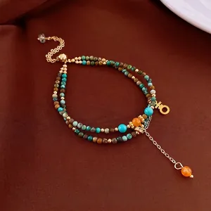 Bracciale in pietre naturali con perline turchesi e ciondoli dorati su seta