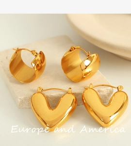 Vue détaillée de boucles d'oreilles dorées en forme de C et de cœurs sur pierre