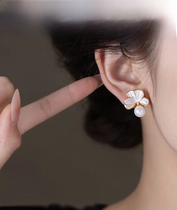 Gros plan de boucles d'oreilles fleurs avec pétales blancs et perles sur un mannequin
