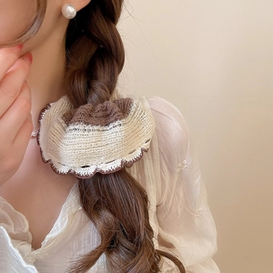 Detail of knitted beige and brown scrunchie styled on a braided low ponytail