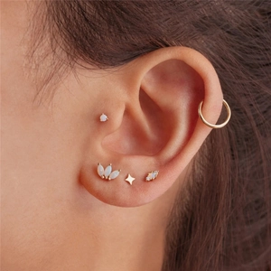 Close-up of 925 sterling silver opal ear piercing set with gold stud earrings and hoops