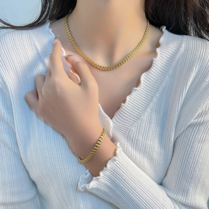 Minimalist gold wheat chain necklace and bracelet set worn by model on white top