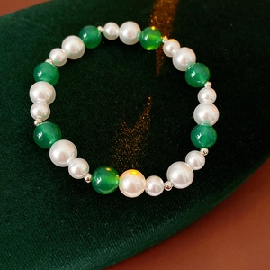 Dettaglio del bracciale vintage con perle bianche e pietre di agata verde su velluto