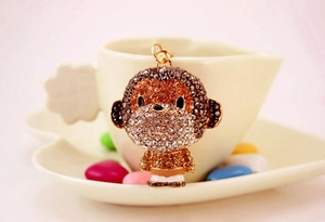 Detail of cute monkey keychain with sparkling brown rhinestones on a white ceramic plate