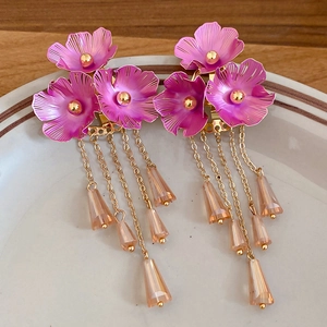Detail von rosa Metallblumen-Ohrringen mit goldenen Quasten und Champagner-Kristallen