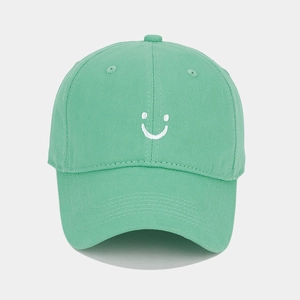 Detailed view of mint green baseball cap with white smiley face embroidery