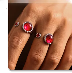 Close-up of silver stainless steel rings featuring red garnet stones worn on fingers