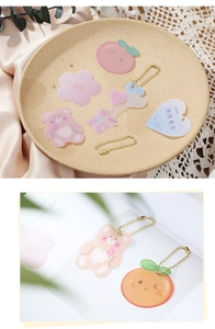 Detail of cute acrylic keychains with gold bead chains on elegant silk and lace background