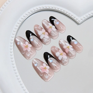 Pink cat-eye press-on nails with 3D camellia flowers and pearl accents in a heart mirror