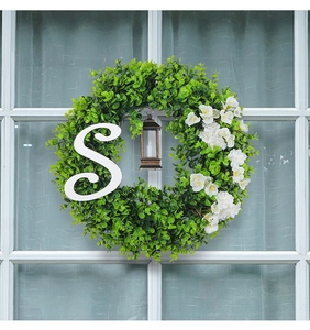 Detail of Christmas eucalyptus wreath with white letter S and vintage LED lantern on a window
