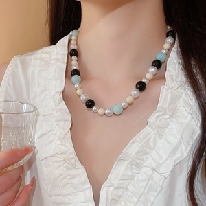 Detail of multi-colored pearl and glass beads necklace on a model with white blouse