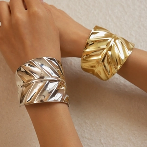 Detailed texture of gold and silver metallic leaf patterned open cuffs on model