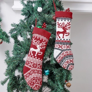 Knitted Christmas stockings with reindeer and snowflake patterns hanging on a Christmas tree