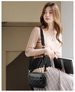 Detail of black quilted crossbody bag with gold hardware and mini round coin purse detail