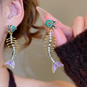 Unique fishbone drop earrings with teal enamel and white pearls on a gold-plated base