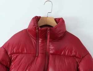 Detail of red shiny high collar puffer jacket featuring a dual zipper and padded texture