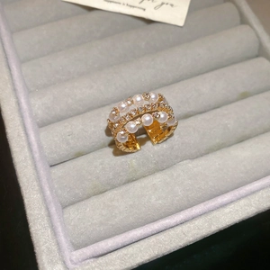 Detail of double-layer gold ring with pearls and zircons on a gray velvet box