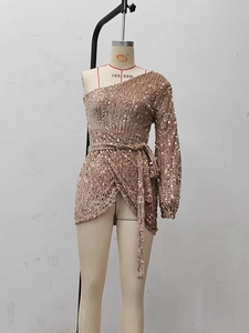 Detail of champagne gold sequined dress showing one-shoulder sleeve and waist tie detail