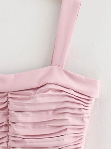 Detailed close-up of light pink dress featuring horizontal ruching and pleated fabric texture