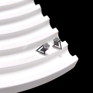 Macro shot of silver geometric earrings featuring petal details on a white wave pedestal