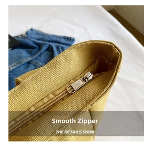 Detail shot of a mustard yellow canvas tote bag showing smooth metal zipper closure