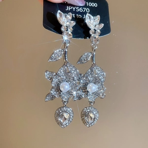 Dettaglio degli orecchini a fiore in argento con cristalli, perle e ciondolo a cuore