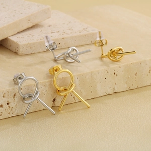 Macro detail of minimalist knotted geometric earrings in gold and silver finish