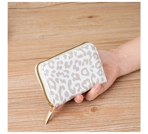 Close-up of a hand holding the leopard print card holder with gold zipper detail