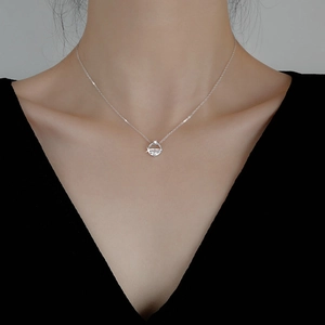Close-up of elegant silver necklace with a sparkling zircon pendant on a model wearing black