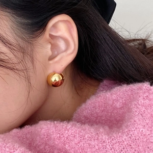 Minimalist S925 sterling silver golden spherical earrings worn on ear for a modern look