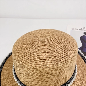 Close-up of vintage straw boater hat featuring pearl lace trim and textured weave pattern