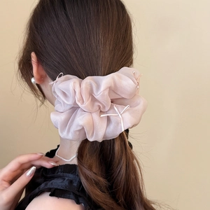 Pink organza scrunchie with cream ribbon bows on a woman's brown ponytail