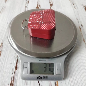 Detailed view of lightweight 31g Christmas tin candy box on a digital scale