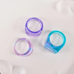 Nahaufnahme von bunten, halbtransparenten Harzringen in Lila, Blau und Pink mit Glitzer