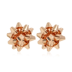 Gros plan de boucles d'oreilles nœuds dorés élégants avec finition métallique polie sur blanc