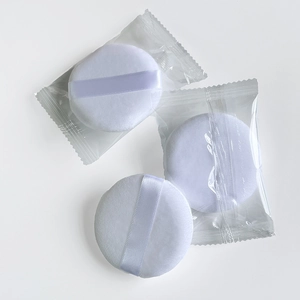Detailed view of three white crystal velvet round powder puffs with satin ribbon handles