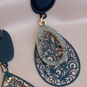 Detailed macro view of black cutout teardrop earrings with embedded grey rhinestones