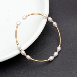 Macro shot of colorful natural freshwater pearls on a gold elastic wire cuff bracelet