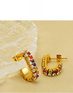 Macro detail of U-shaped gold earrings with colorful rhinestones and butterfly backs