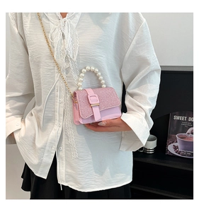 Close-up of pink sequined mini handbag with pearl handle and golden chain strap