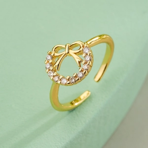 Elegant gold-plated bow ring with cubic zirconia on a light green background
